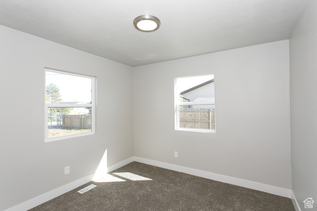 Carpeted empty room featuring baseboards and visible vents