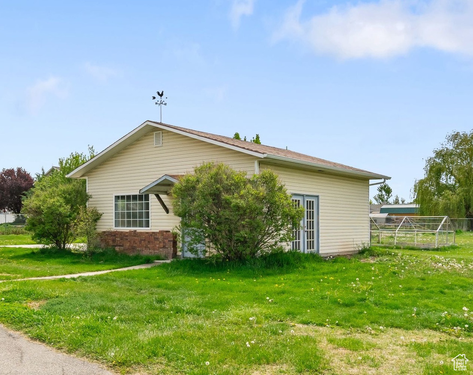 View of home\\\'s exterior featuring fence, a lawn, and brick siding