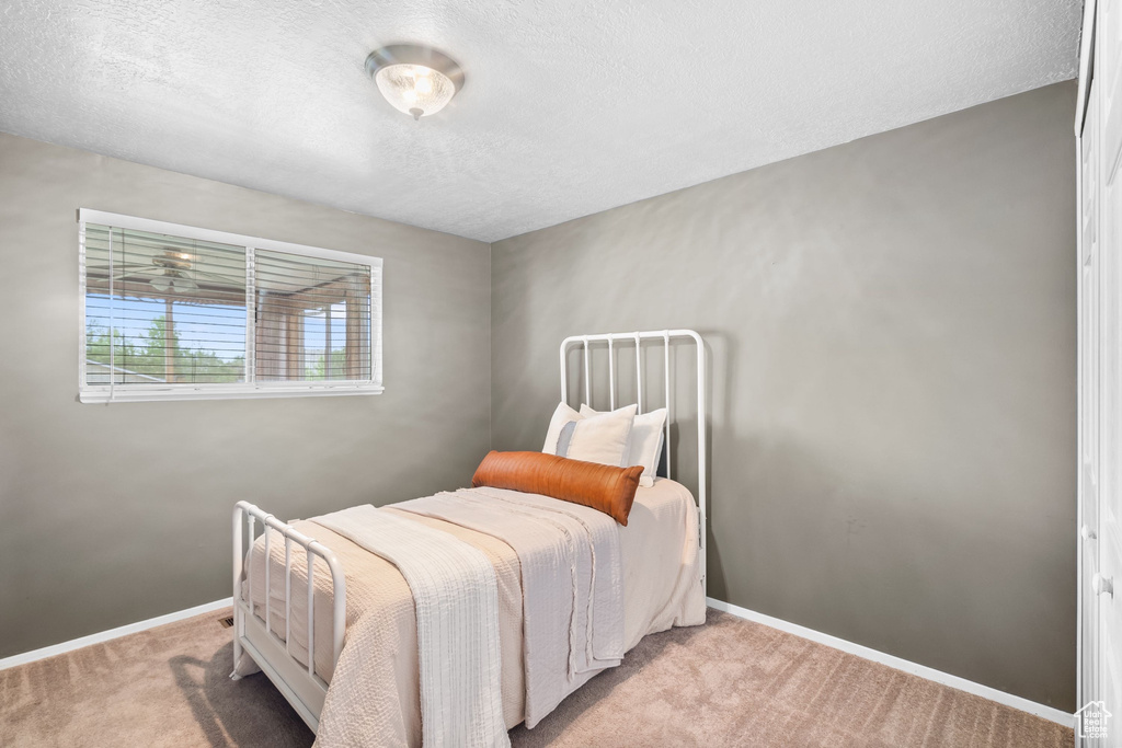 Carpeted bedroom with baseboards and a textured ceiling