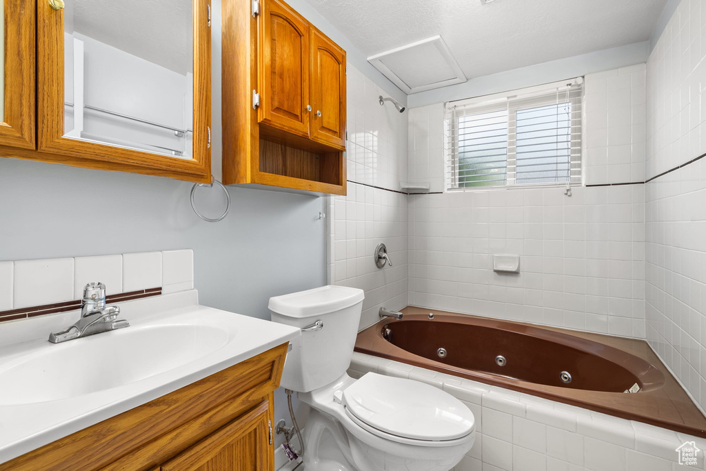 Full bathroom featuring vanity, a combined bath / shower with jetted tub, and toilet