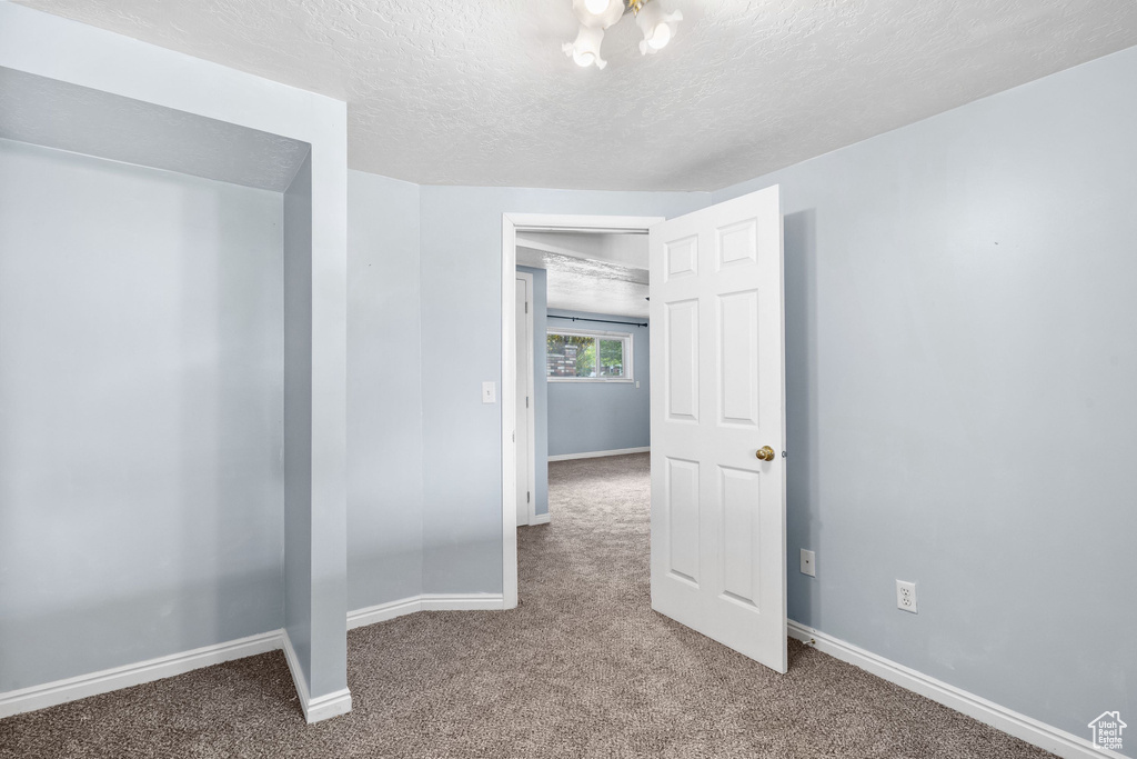 Carpeted empty room with baseboards and a textured ceiling