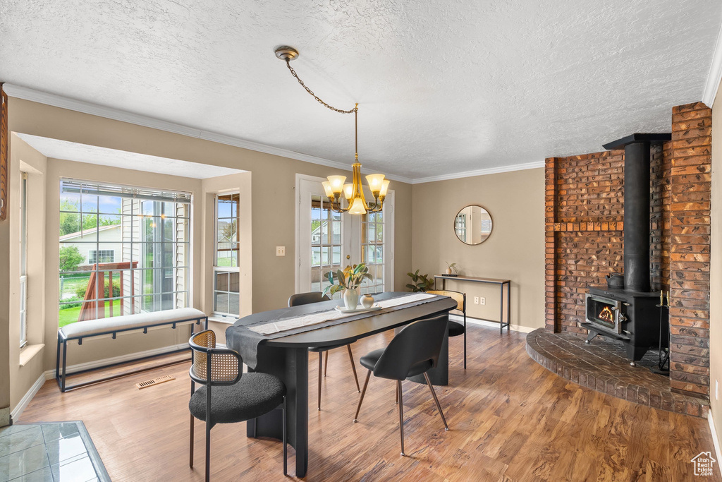 Dining space with a textured ceiling, a chandelier, plenty of natural light, and wood finished floors