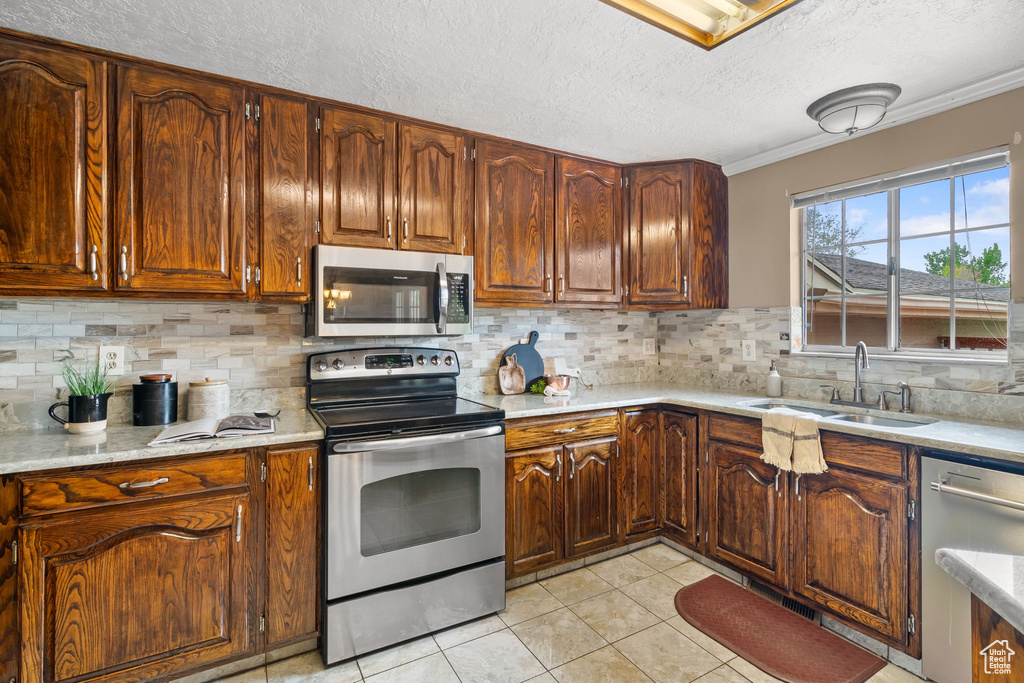 Kitchen with a sink, appliances with stainless steel finishes, a textured ceiling, and light countertops