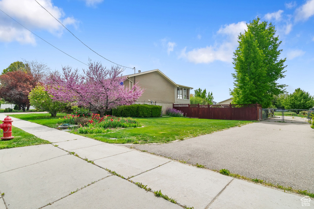 View of side of home featuring fence, a gate, and a lawn