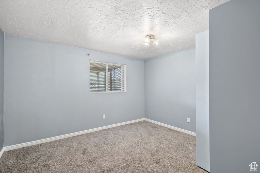 Carpeted empty room featuring baseboards and a textured ceiling