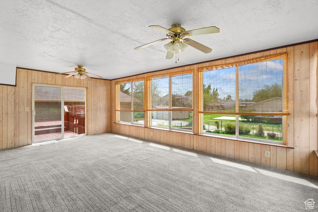Interior space featuring wooden walls, a textured ceiling, and carpet floors