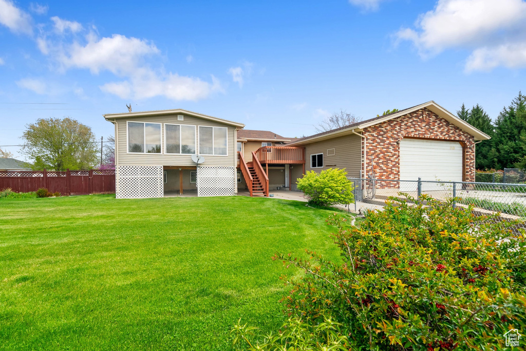 View of front facade featuring stairs, brick siding, a garage, a front yard, and a fenced backyard