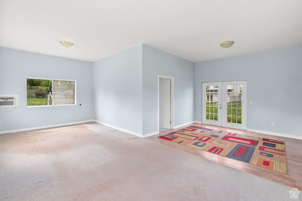 Unfurnished room featuring carpet flooring, baseboards, french doors, and a wall mounted air conditioner