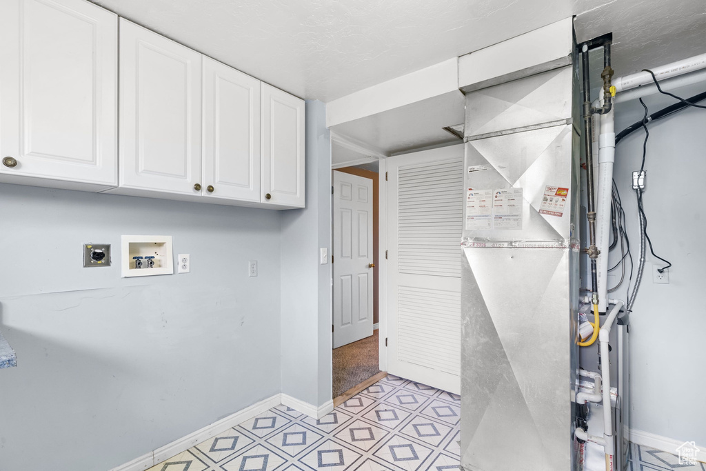 Laundry room with hookup for an electric dryer, cabinet space, baseboards, hookup for a washing machine, and light tile patterned flooring