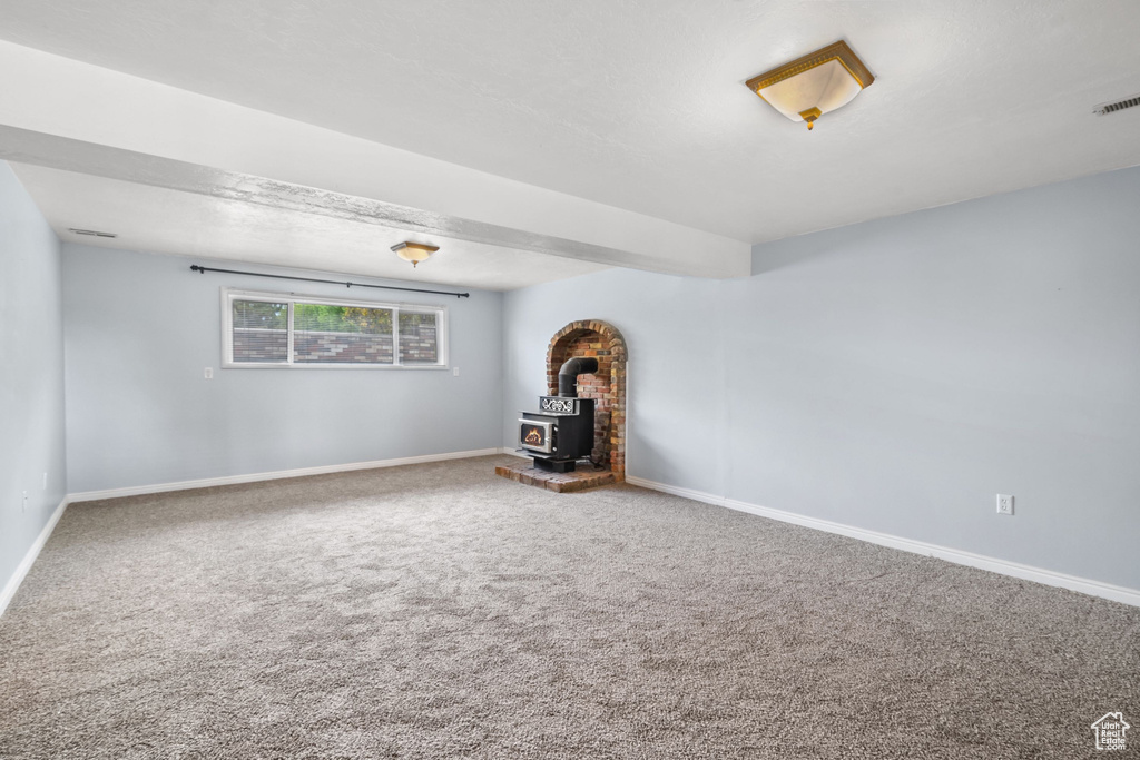 Interior space featuring carpet floors, a wood stove, and baseboards