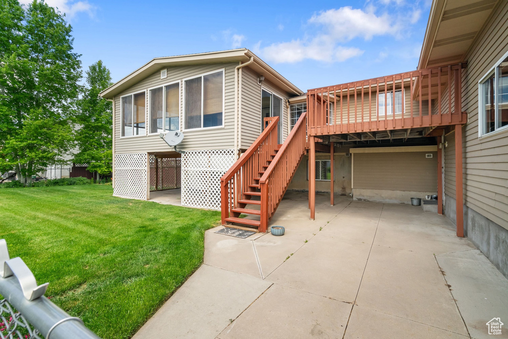 Rear view of property with a lawn, a deck, a sunroom, and stairway