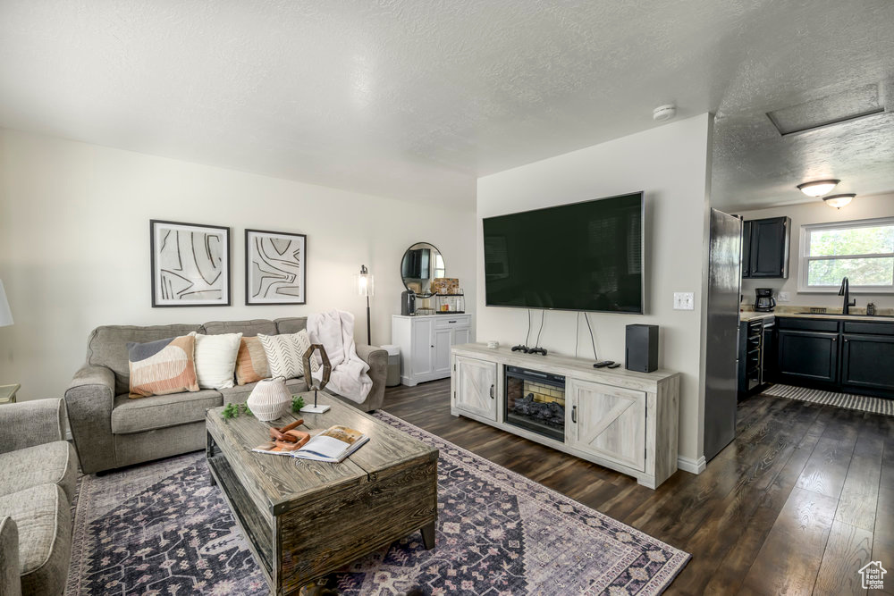 Living area with a textured ceiling, dark wood-style floors, and baseboards