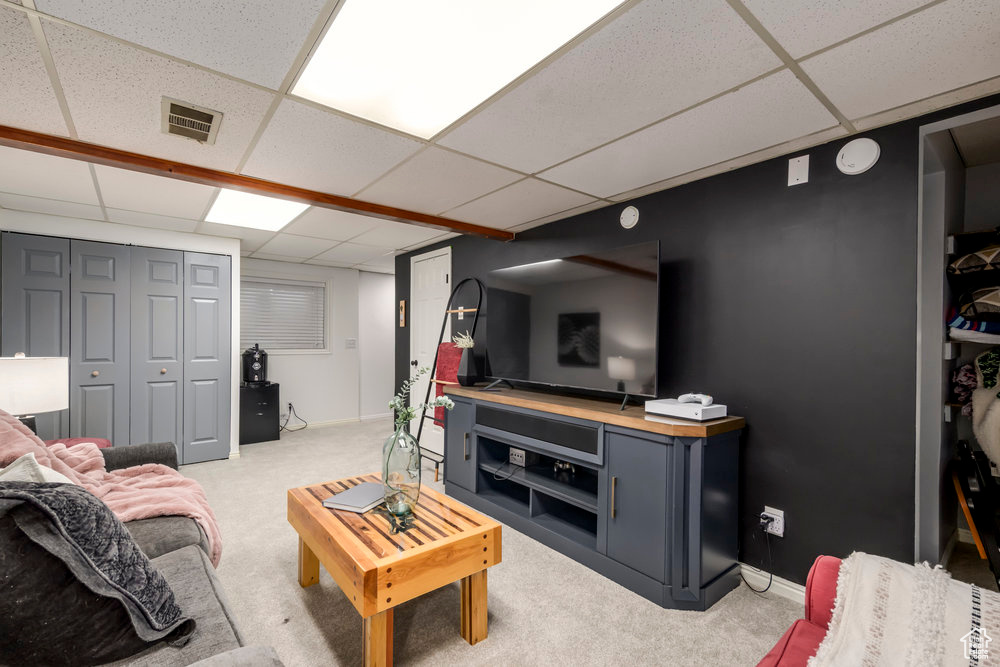 Living room with visible vents, a paneled ceiling, baseboards, and light carpet
