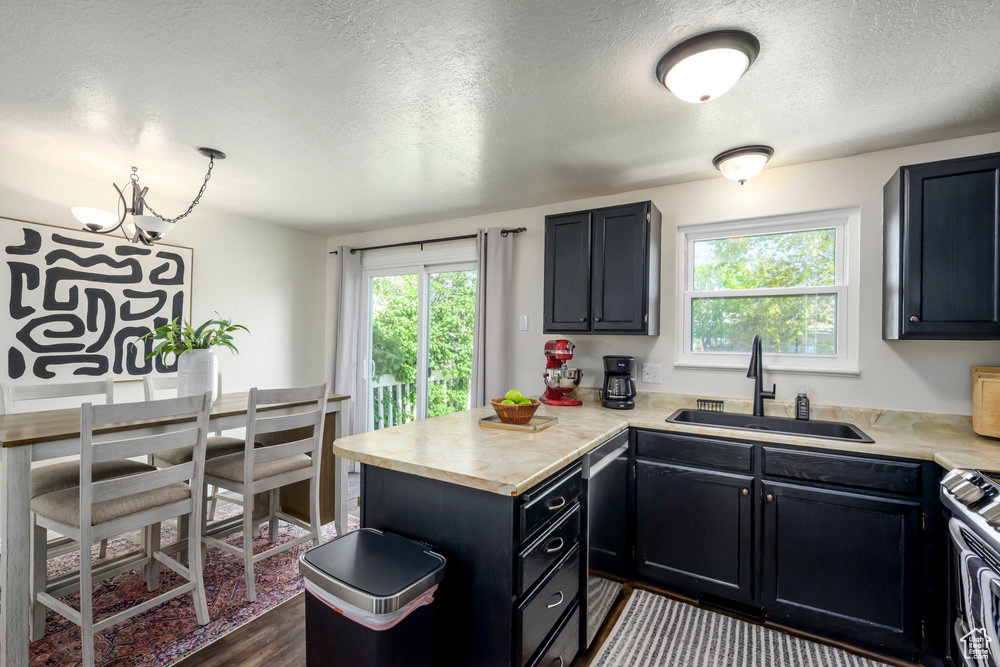 Kitchen with a textured ceiling, a sink, light countertops, a peninsula, and stainless steel appliances