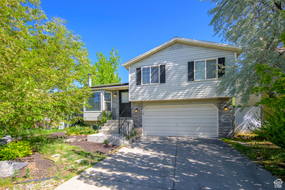 Tri-level home featuring concrete driveway, brick siding, and a garage