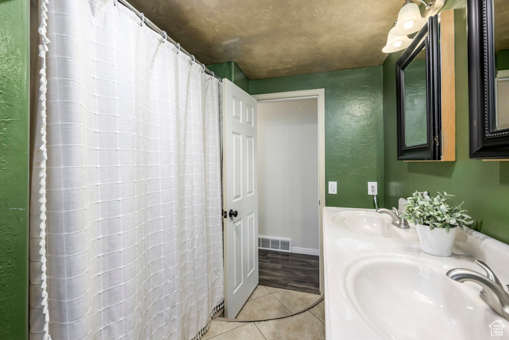 Bathroom featuring visible vents, a sink, a shower with shower curtain, and tile patterned flooring