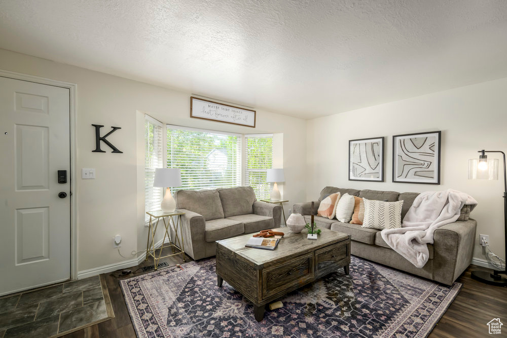 Living area featuring baseboards, a textured ceiling, and wood finished floors