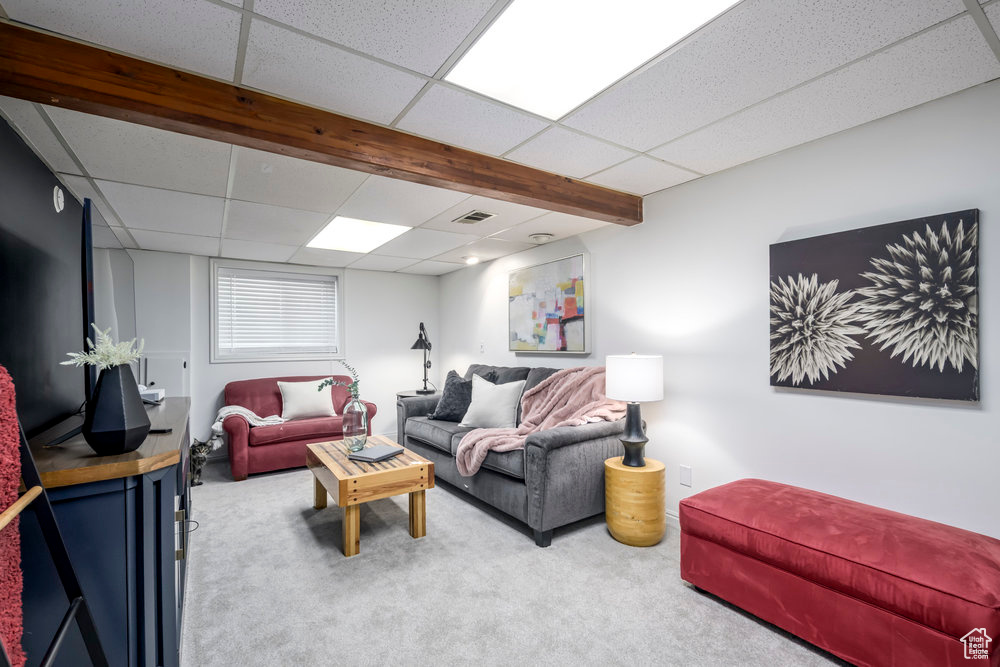 Carpeted living room with visible vents and a drop ceiling