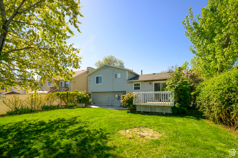 Rear view of house featuring a lawn and a wooden deck