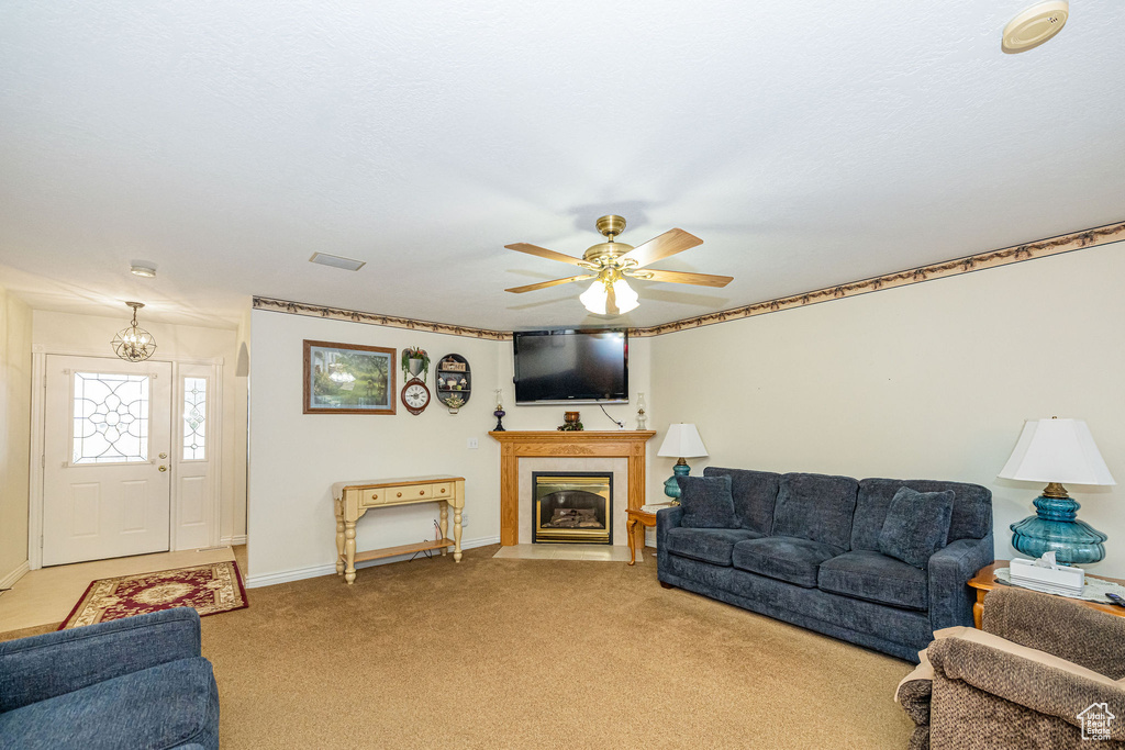 Living room with visible vents, baseboards, ceiling fan, light colored carpet, and a fireplace with flush hearth