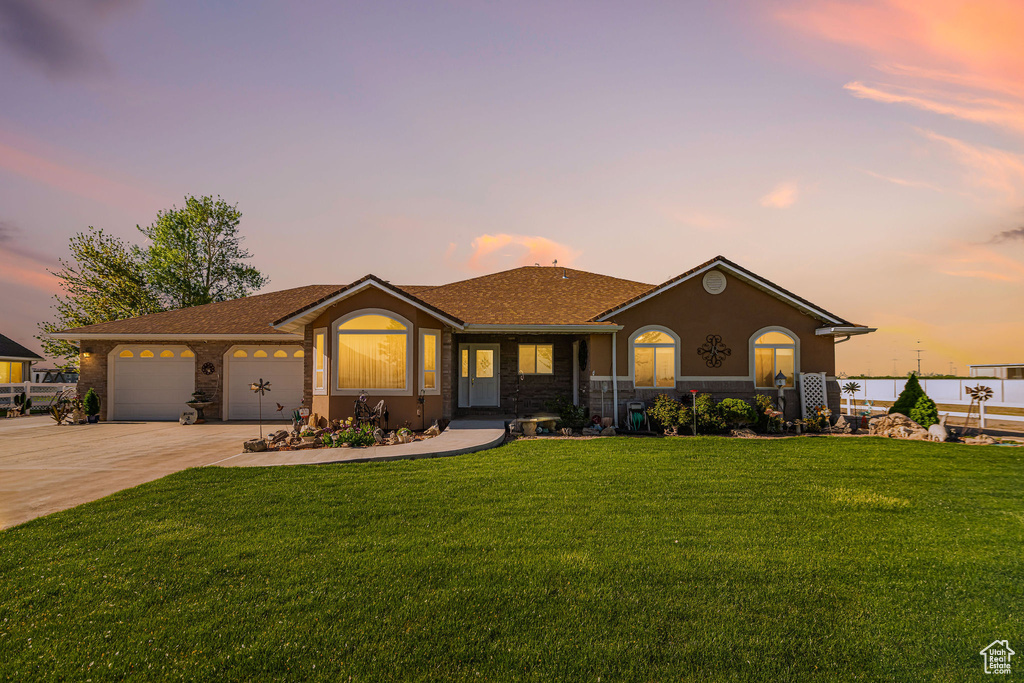 Ranch-style home with an attached garage, stucco siding, a front yard, and concrete driveway