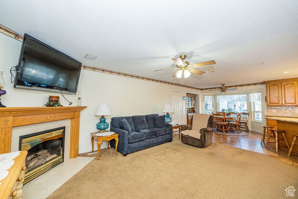Living room with baseboards, ceiling fan, light tile patterned floors, and a tile fireplace