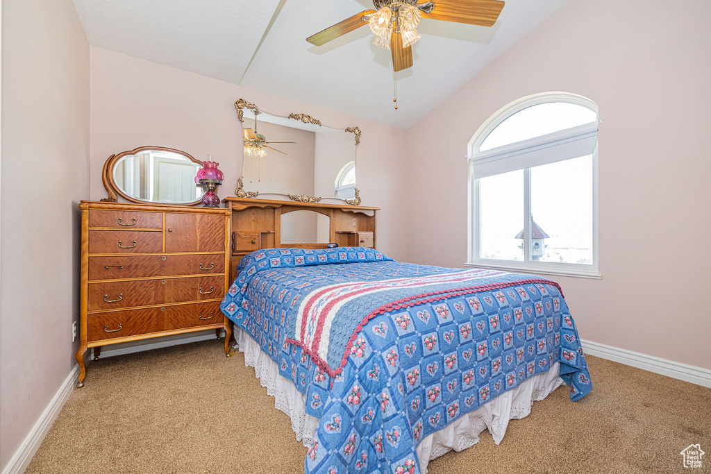 Carpeted bedroom with baseboards, ceiling fan, and vaulted ceiling