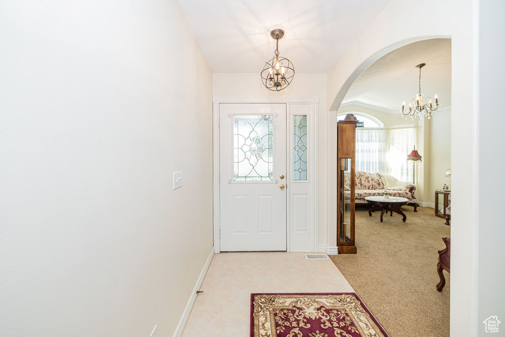 Entrance foyer featuring an inviting chandelier, arched walkways, and baseboards