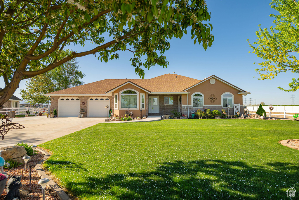Ranch-style house with fence, an attached garage, driveway, and a front yard