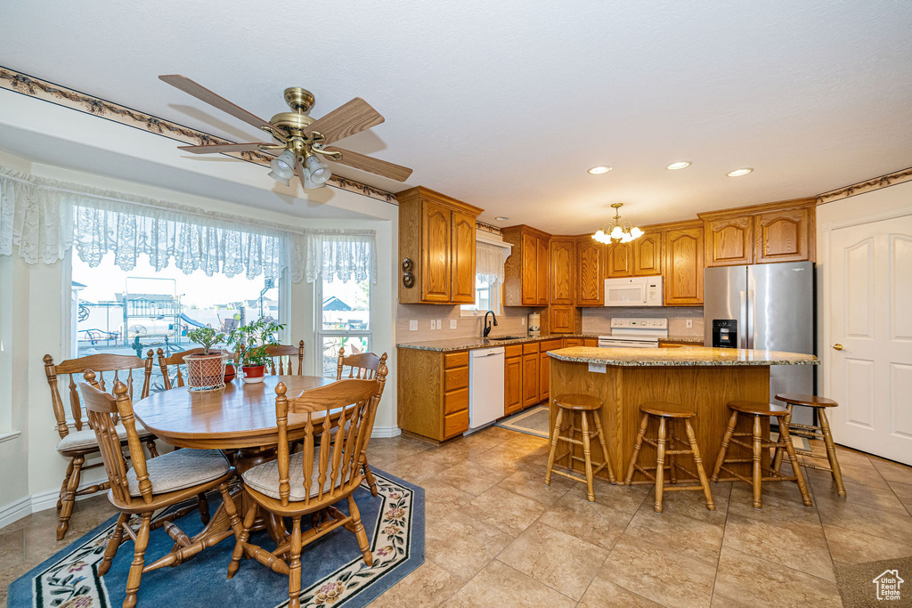 Kitchen featuring a kitchen island, a sink, ceiling fan with notable chandelier, recessed lighting, and white appliances