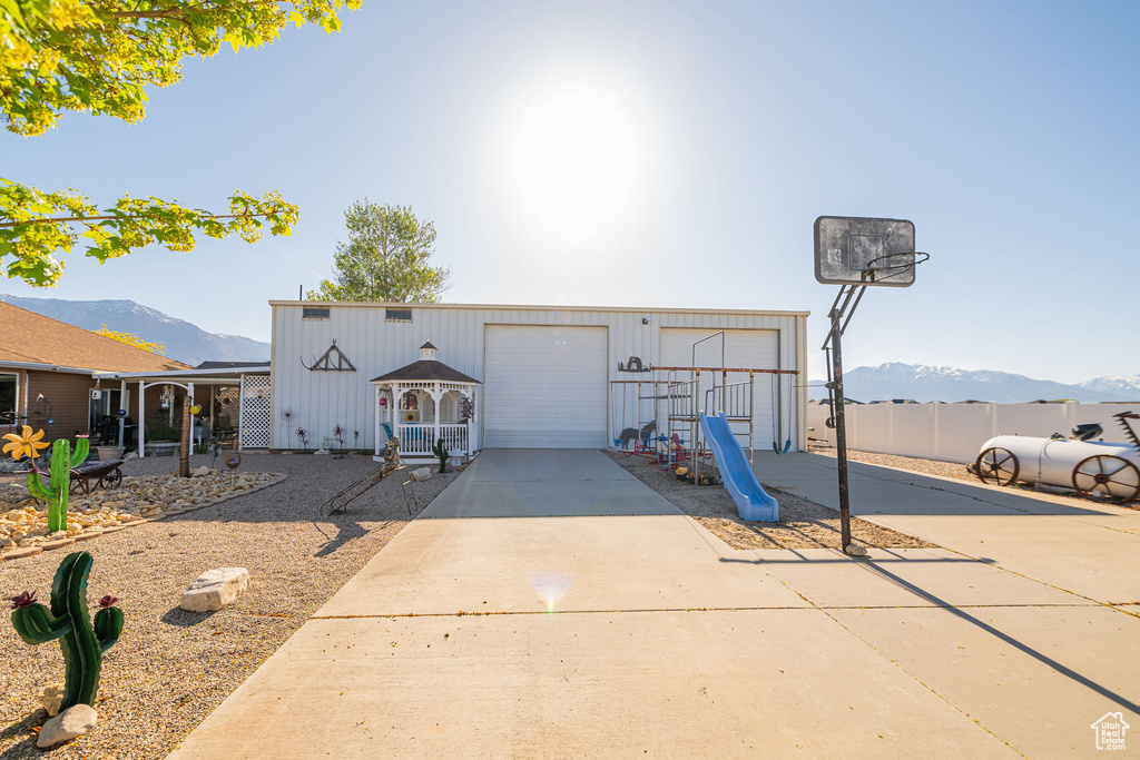View of front of property featuring fence, driveway, a mountain view, and a garage