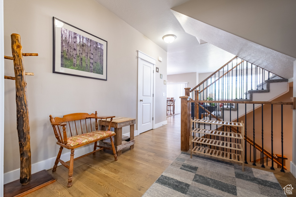 Corridor with wood finished floors, baseboards, and stairway