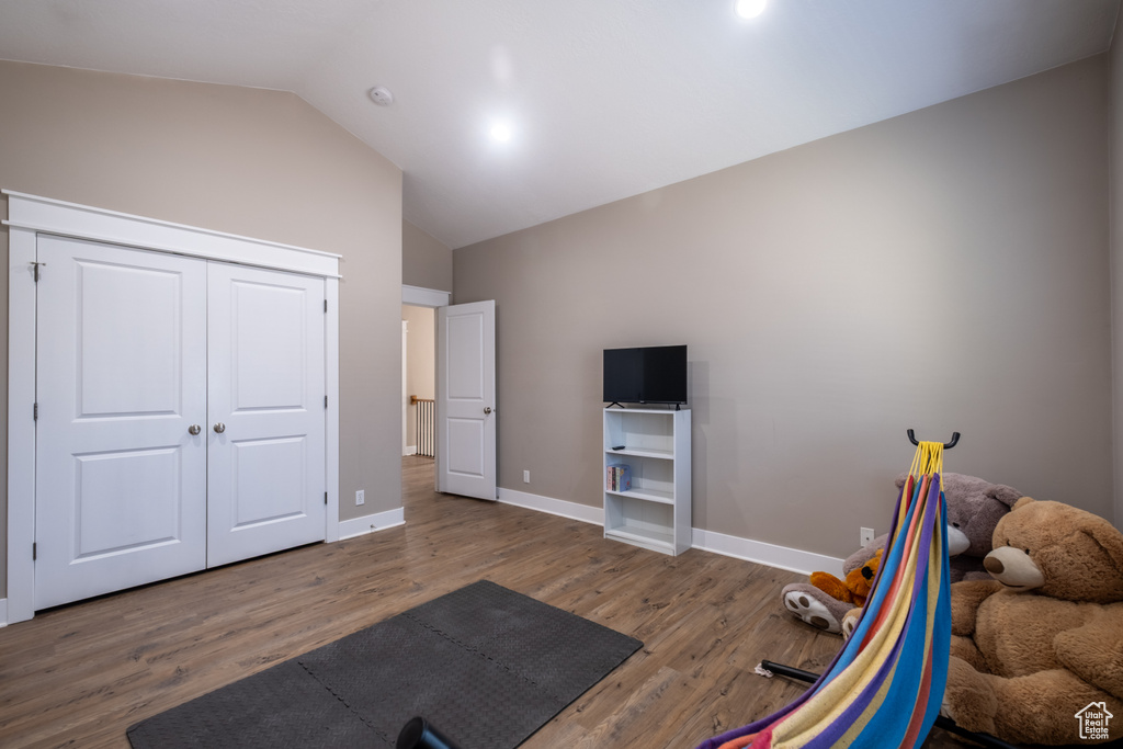 Workout area with wood finished floors, lofted ceiling, and baseboards