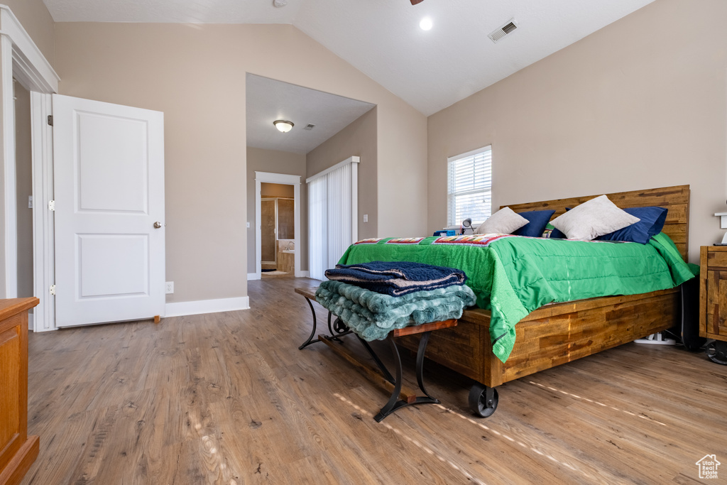 Bedroom with wood finished floors, baseboards, and high vaulted ceiling