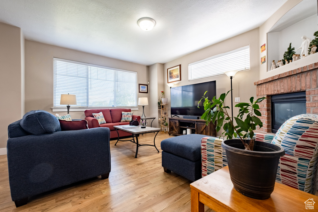 Living area with healthy amount of natural light, light wood finished floors, and a brick fireplace