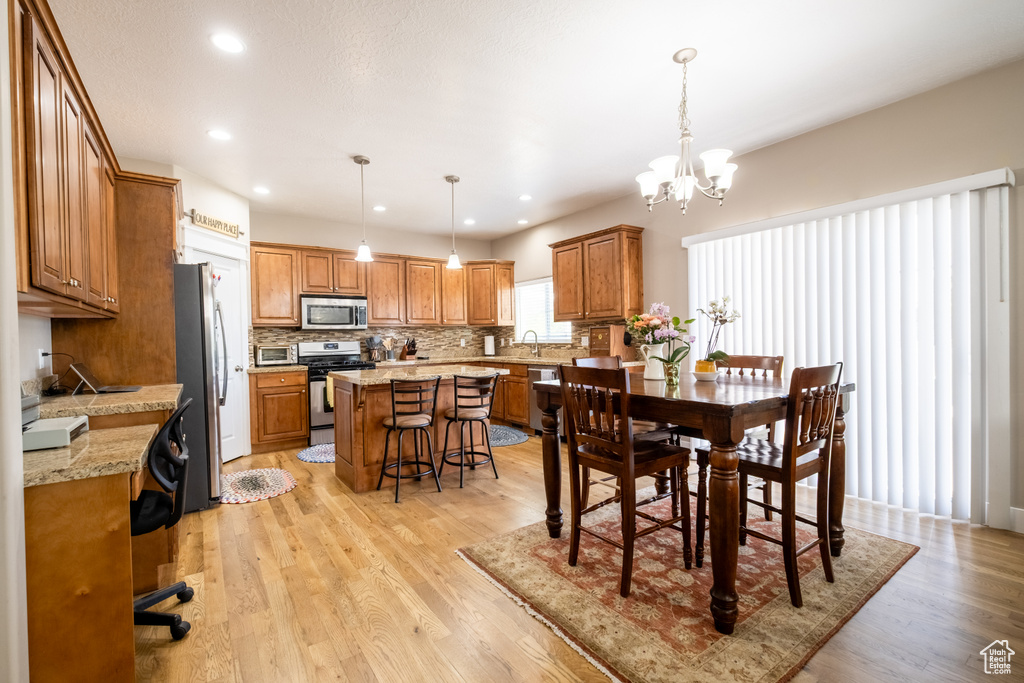 Dining space with light wood-type flooring, a chandelier, and recessed lighting