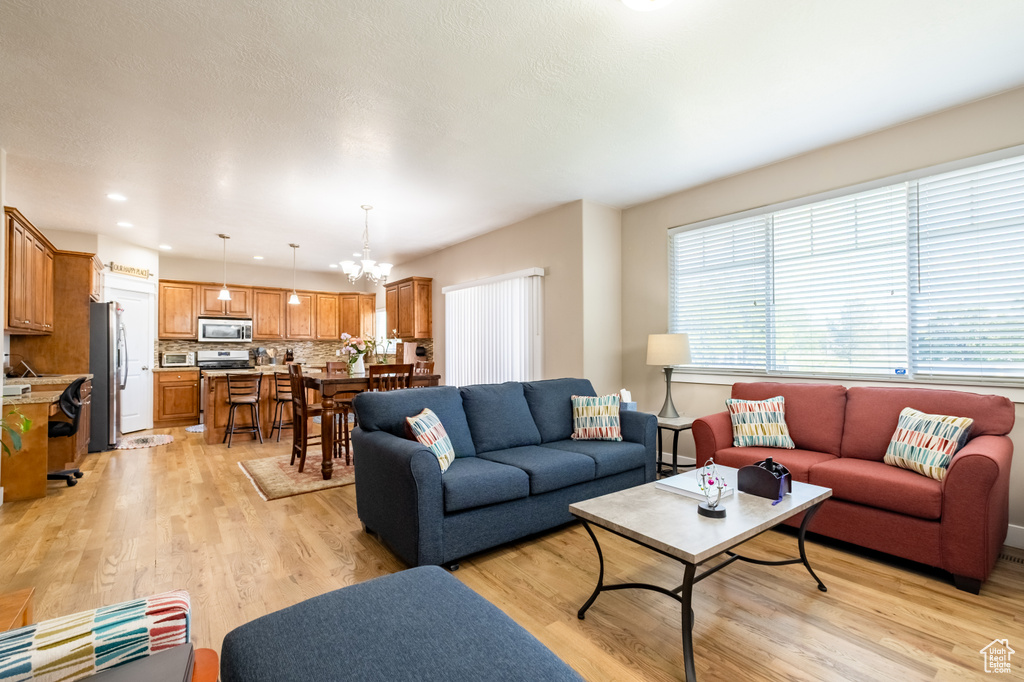 Living room featuring light wood-type flooring, a chandelier, and recessed lighting