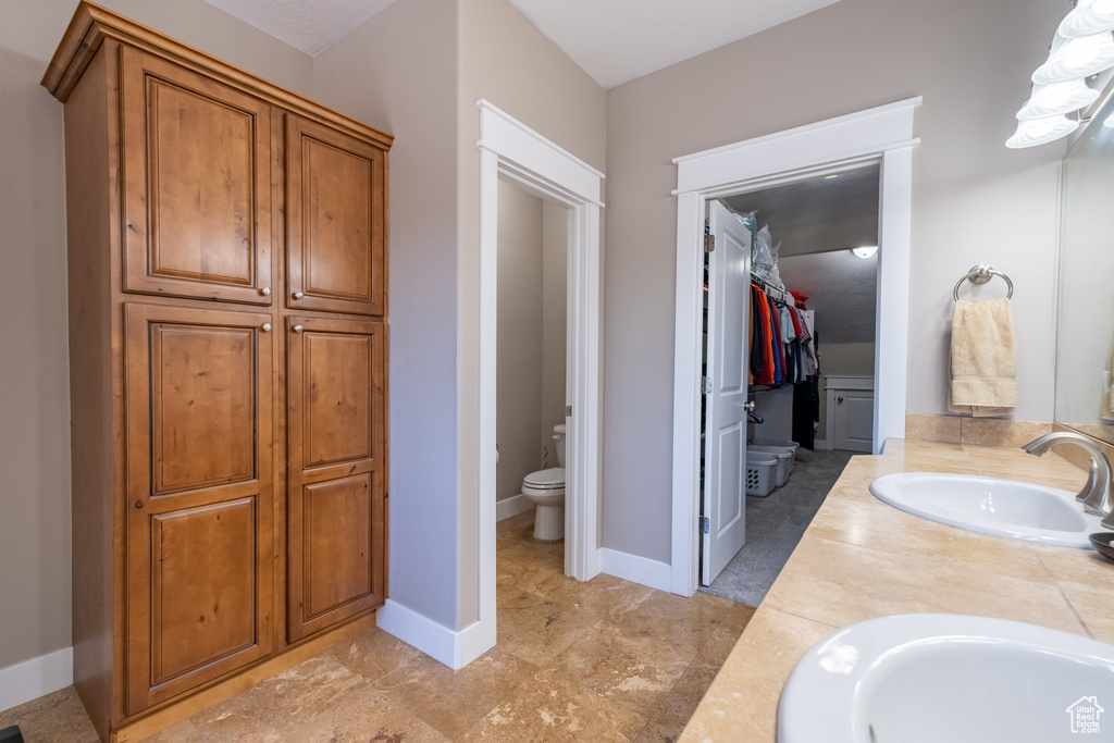 Full bath featuring toilet, double vanity, and a spacious closet