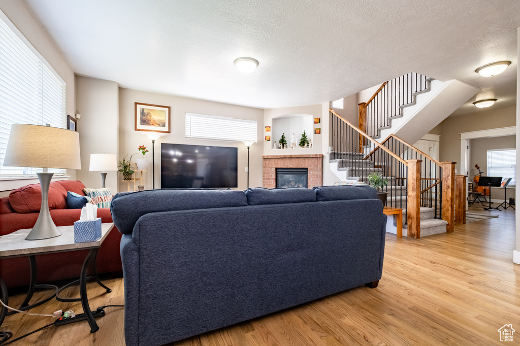 Living area featuring a brick fireplace, stairs, and light wood-style floors