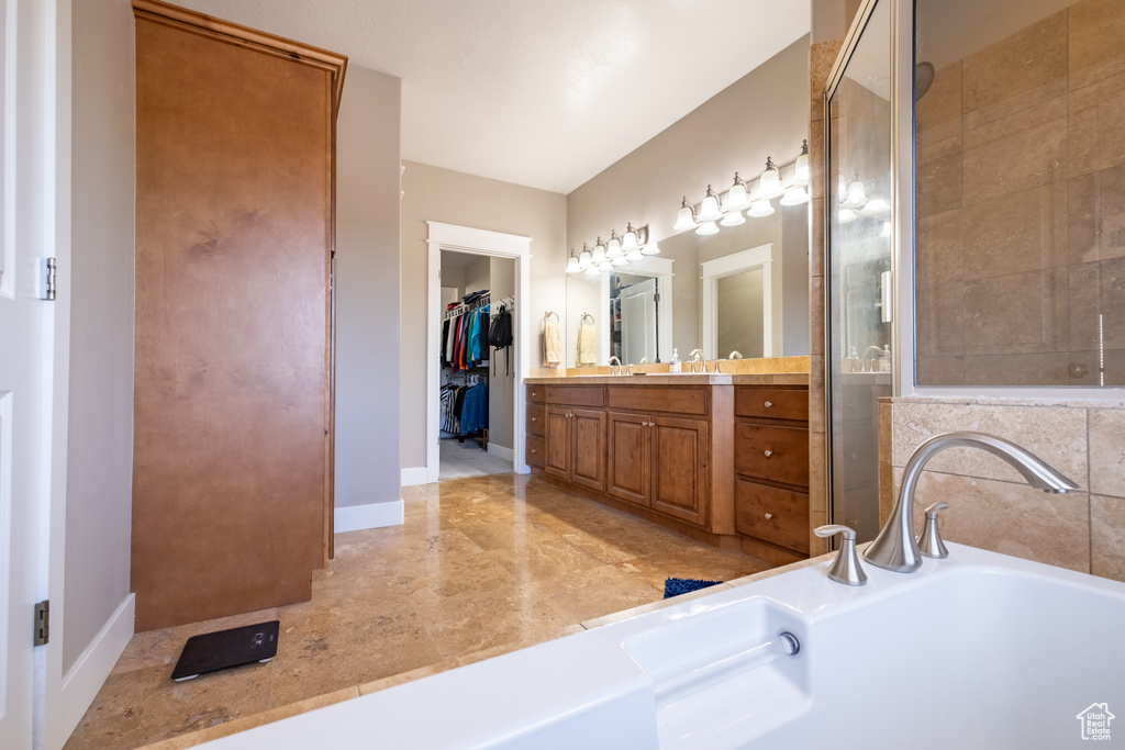 Bathroom with a bath, a shower stall, vanity, and baseboards