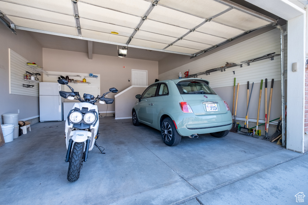 Garage featuring a garage door opener and freestanding refrigerator