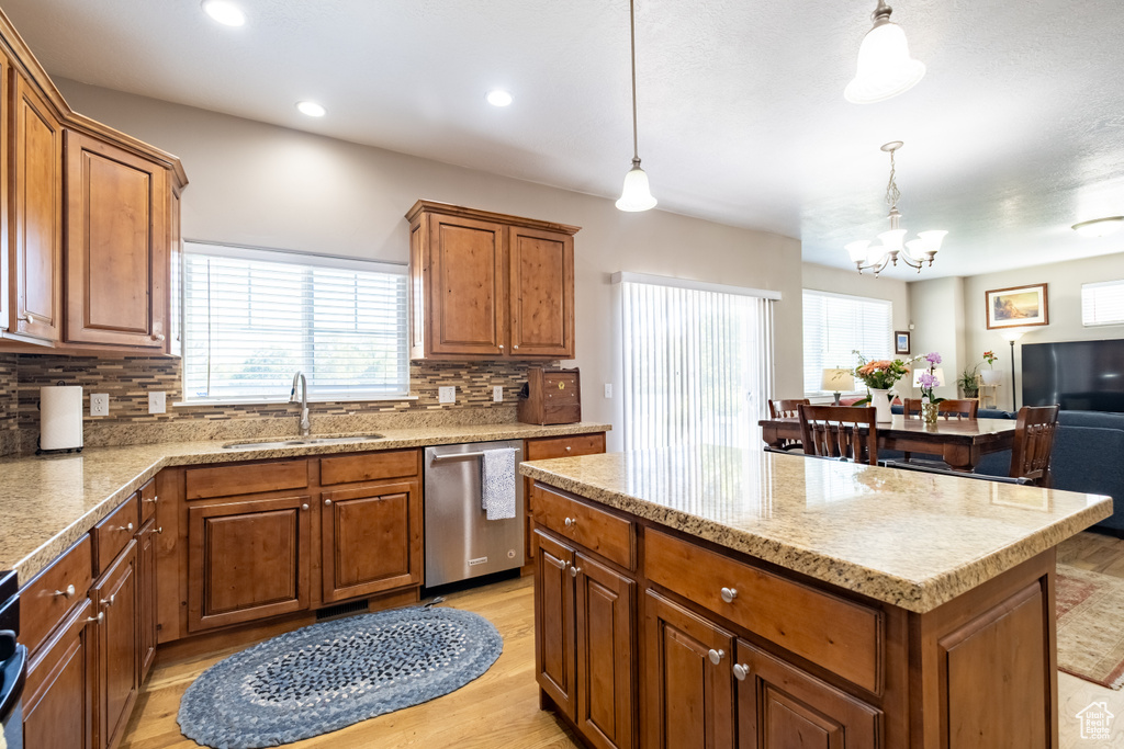 Kitchen with a sink, stainless steel dishwasher, a chandelier, light wood-type flooring, and brown cabinets