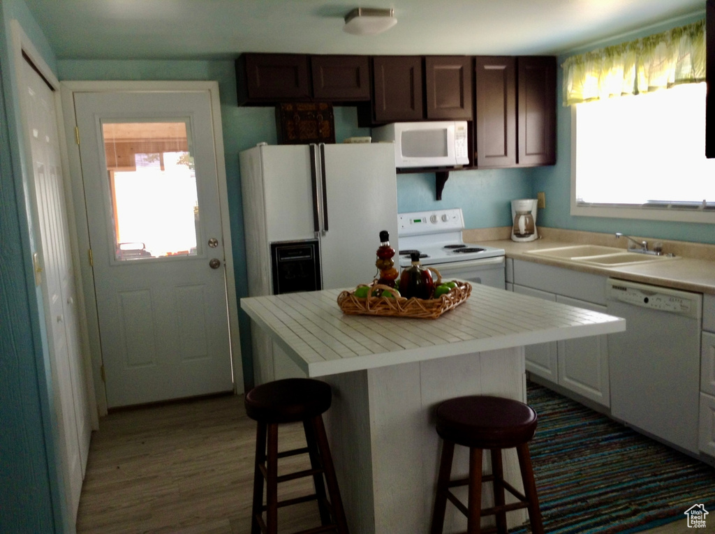 Kitchen featuring a sink, a breakfast bar, a healthy amount of sunlight, and white appliances