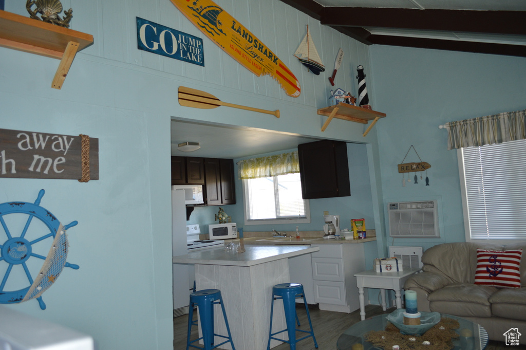 Kitchen with light countertops, a kitchen bar, dark wood-type flooring, and white microwave