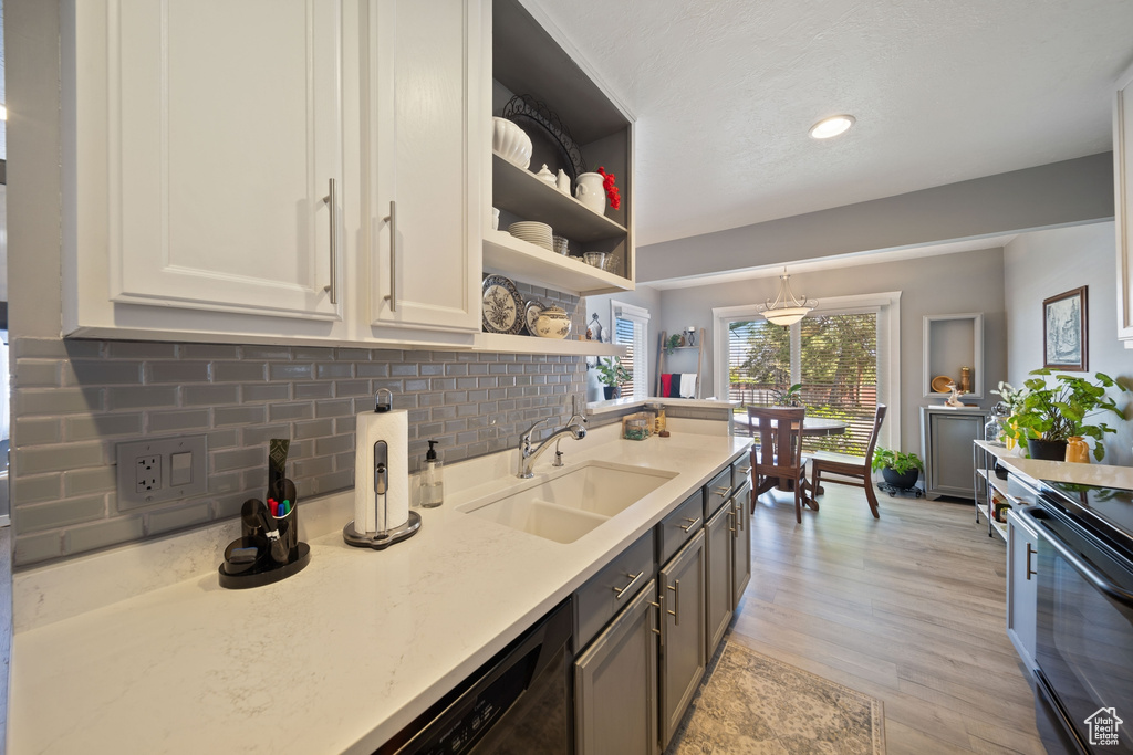 Kitchen with open shelves, a sink, light wood-style flooring, backsplash, and black / electric stove