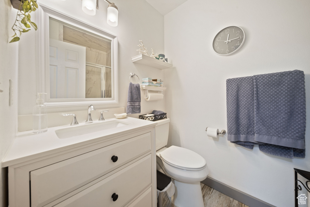 Full bathroom featuring toilet, a shower with door, wood finished floors, and vanity