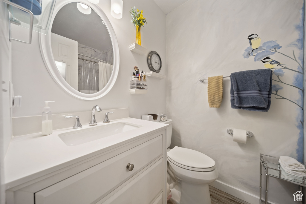 Full bath featuring vanity, curtained shower, toilet, and wood finished floors