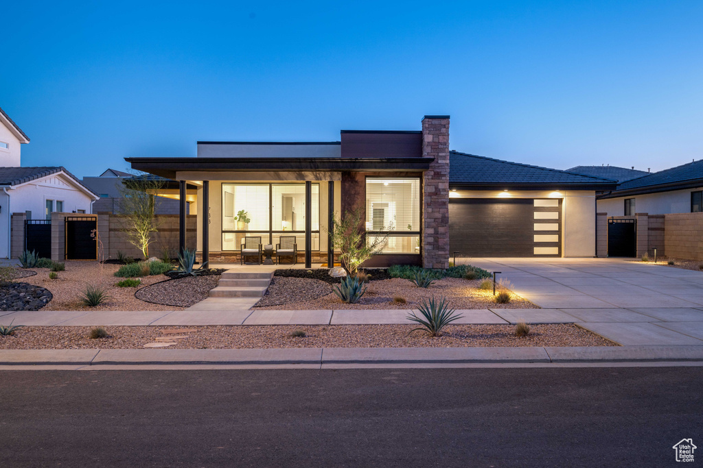Contemporary home with fence, covered porch, an attached garage, and concrete driveway