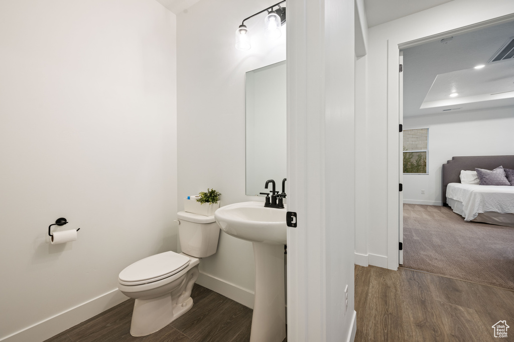 Bathroom with baseboards, toilet, and wood finished floors