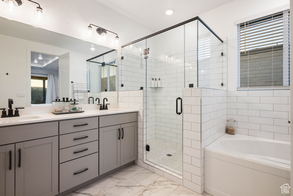Full bathroom featuring a sink, double vanity, marble finish floor, a bath, and a stall shower